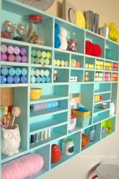 a turquoise open storage unit with lots of small shelves inside