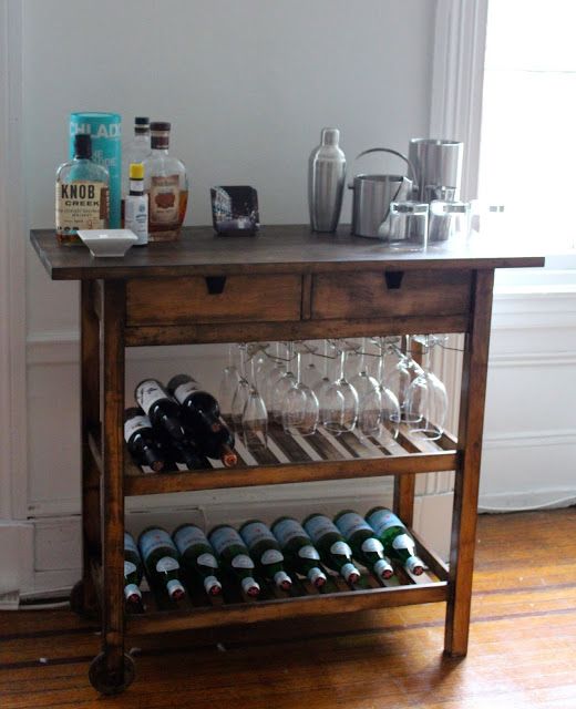 a dark stained Ikea Forhoja cart used as a home bar with lots of glasses, bottles, barware and other necessary stuff