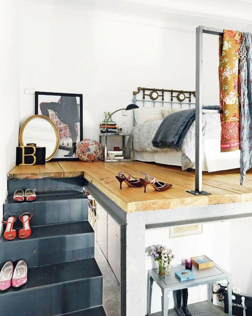 a lovely loft bedroom with a metal bed, artwork and a mirror, shoes as decor and some printed and bold blankets