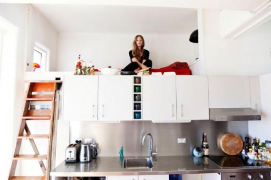 a tiny loft bedroom placed right on the kitchen cabinets allows you to have a separate sleeping space even in a very small apartment