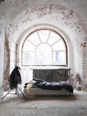 an industrial bedroom featuring whitewashed brick walls and an arched ceiling plus a concrete floor looks raw and statement