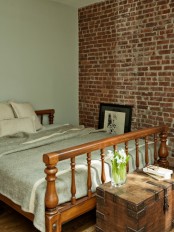 a small vintage-inspired bedroom with wooden furniture and a red brick statement wall that adds texture and a bright shade to the space