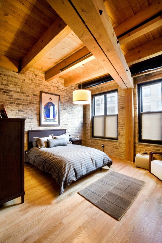 a welcoming modern bedroom with dark stained furniture, wooden beams and an exposed brick wall - both these features add interest to the space