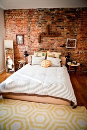 an eclectic bedroom is made catchier with an exposed brick wall that also brings a touch of color