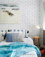a coastal inspired bedroom with a white brick headboard wall that adds texture and makes the space edgier