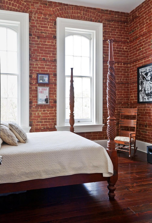 red brick walls, a redwood floor and redwood bed create an elegant bedroom in the reddish shades