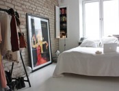 a Nordic bedroom with a brick wall, a white floor and an open closet features raw and simple aesthetics