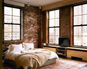 a stylish bedroom with brick walls, plywood furniture and boho rugs plus an upholstered bed