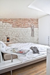 an ultra-modern bedroom with a chic bed is made bolder and catchier with a faux stone and brick wall created with a mural