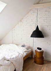 a Nordic guest bedroom with a fake white brick wall, a black lamp and wooden furniture