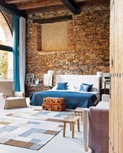 an eclectic bedroom with a stone wall, contemporary and vintage furniture and a glazed wall for more light and enjoying views