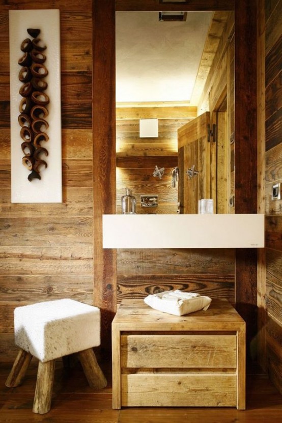 a light-stained wood chalet bathroom completely covered with wood, with a modern sink, a mirror and a white pouf