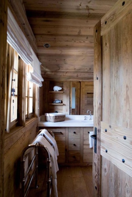 a light-stained chalet bathroom clad with wood, with all wood everything, a large mirror, built-in shelves and neutral textiles