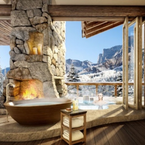 a chalet bathroom with a stone fireplace, a wooden bathtub, folding doors and gorgeous views is amazing