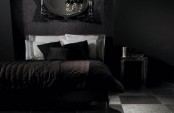 a simple Gothic bedroom with black wallpaper, simpel furniture and black texiles, an oversized black framed mirror over the bed