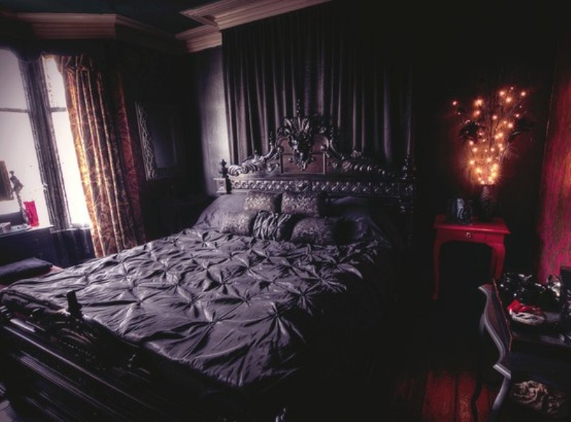 a chic Gothic bedroom with black paneled walls, a black carved wooden bed, dark furniture and textiles and a fuchsia nightstand