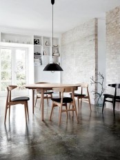 a Nordic dining room with whitewashed red brick walls, built-in shelves and a chic modern dining set with a black pendant lamp over it