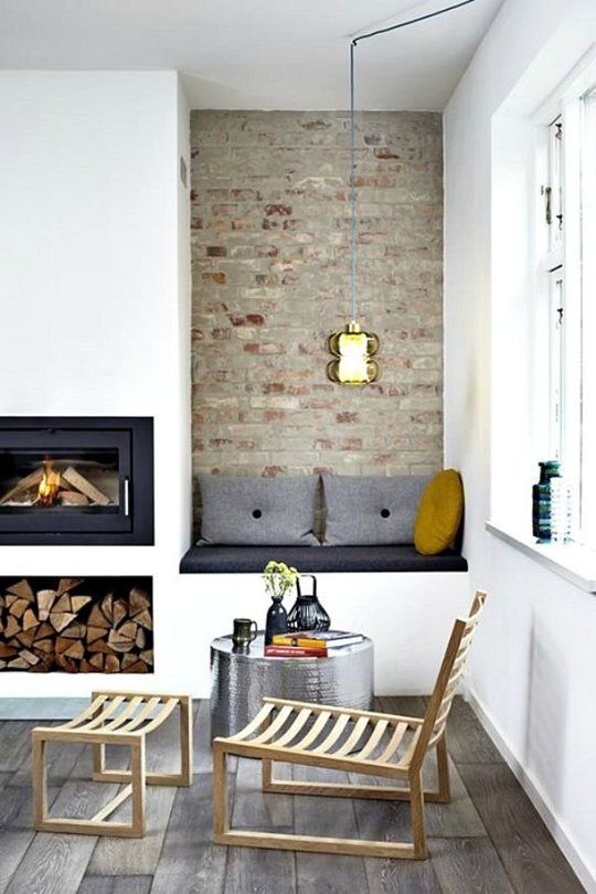 a Scandinavian space with a built-in fireplace and firewood storage, an upholstered built-in bench with pillows is a welcoming and cool nook
