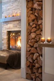 a welcoming space with a built-in fireplace clad with faux stone, a leather ottoman with a blanket and some candles around