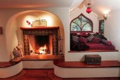 a fireplace clad with tiles with a long step around it that might be used as a bench to enjoy warmth and coziness