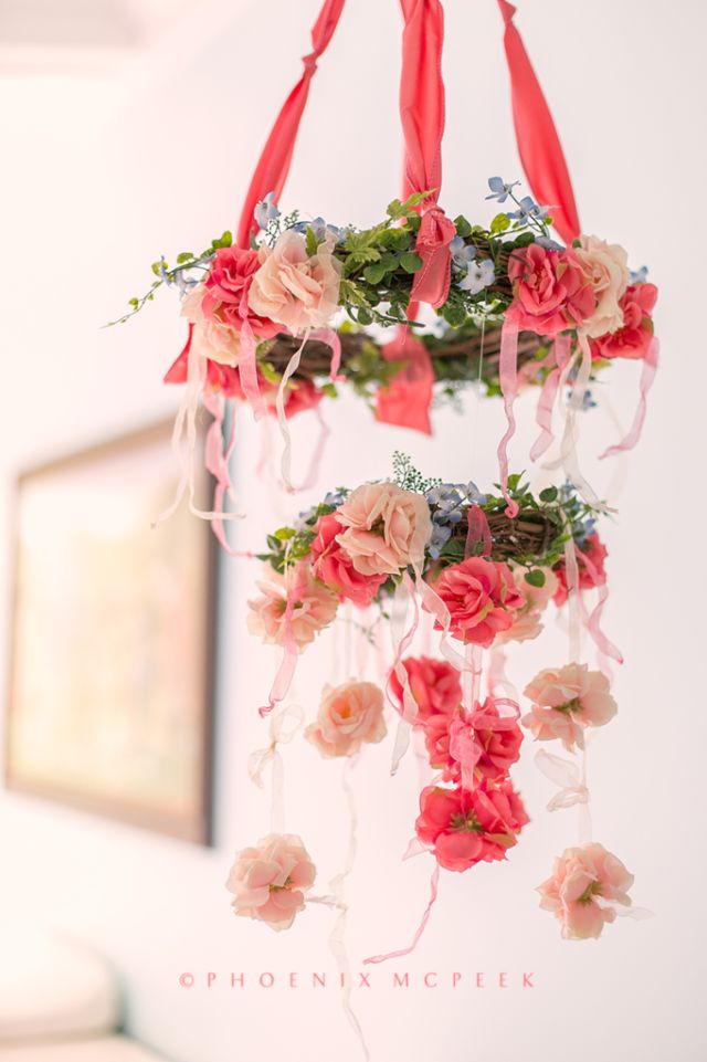 a bright floral nursery mobile of vine wreaths covered with moss, greenery and blooms, with coral and blush fabric blooms hanging down is awesome