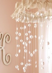 a beautiful nursery mobile with a fabric cover and crystal pendants hanging down is a glam and chic idea for a glam nursery