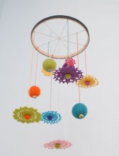 a colorful nursery mobile with bright felt balls and doilies, colorful pompoms is a fun and cool idea for a bright nursery