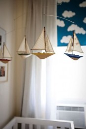 a sea-themed nursery mobile with muted color boats hanging over the crib is a cool idea for a coastal or seaside nursery