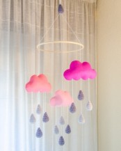 a colorful nursery mobile with bright pink clouds of various shades and grey raindrops of fabric is a catchy and cool idea to rock