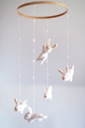 a neutral nursery mobile with funny white felt bunnies is a cool decoration for any neutral nursery