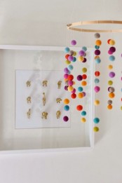 a simple colorful pompom nursery mobile is a very fun and cool solution that can be easily DIYed and you can make it yourself