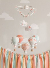a cool muted color nursery mobile with paper hot air balloons and buntings is a very fun and cute idea for a gender-neutral space