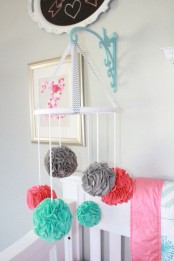 a simple and bold nursery mobile made of colorful felt pompoms can be easily DIYed by you yourself