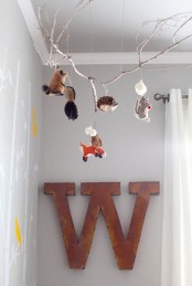 a super cool nursery mobile of a branch with felt mini animals is a lovely idea for a forest-themed nursery