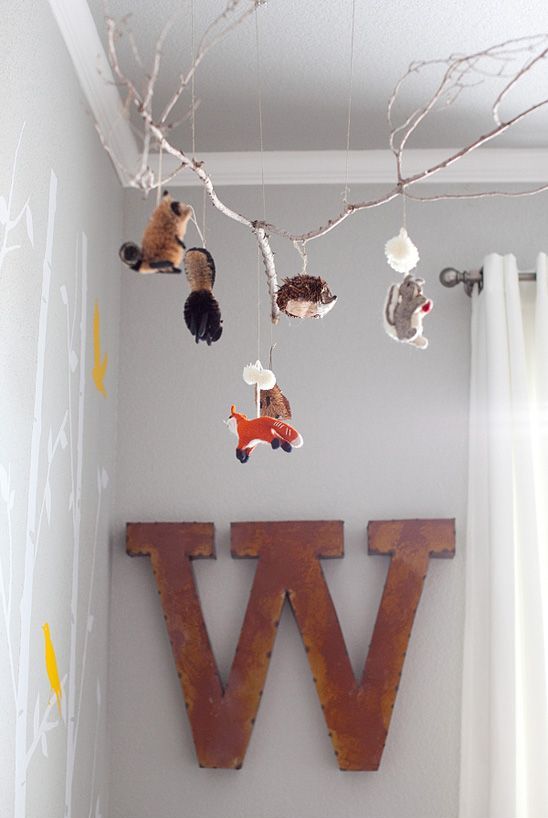 a super cool nursery mobile of a branch with felt mini animals is a lovely idea for a forest themed nursery