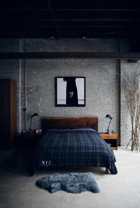 an industrial bedroom with grey brick walls, stained wooden furniture, black table lamps and branches for decor is a cool idea