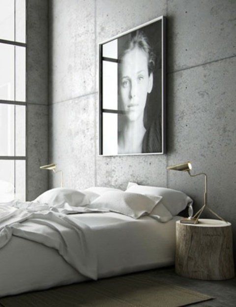 a minimalist industrial bedroom with concrete walls, a bed with neutral bedding, an artwork, nightstand and elegant table lamps