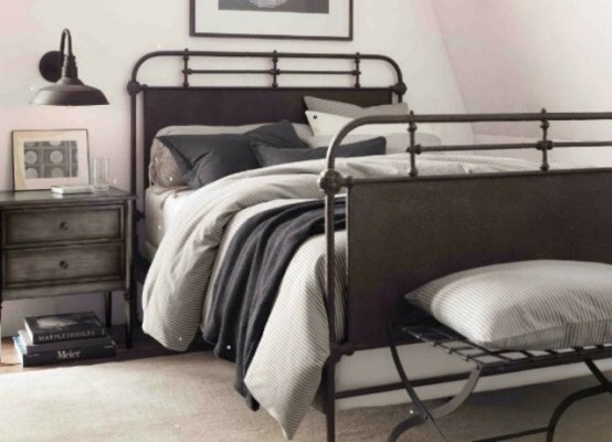 a bedroom with industrial furniture, a metal bed with grey bedding, a reclaimed wood and metal nightstand, some simple grey bedding