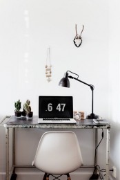 a small Nordic working nook with an industrial metal desk, a white chair, a black metal lamp and potted cacti