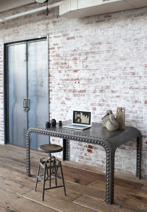 a catchy industrial home office space with whitewashed brick walls, a catchy metal desk, a metal stool and some wabi sabi decor