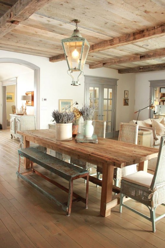 a vintage Provence dining room with a rough wooden table and wicker chairs and a bench, a vintage pendant lamp and some lavender in a vase