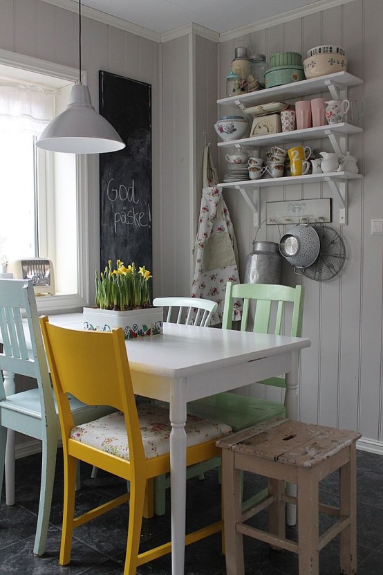 a vintage neutral dining space with shelves on the wall, a white table and mismatching chairs, pastel floral prints and a chalkboard to leave notes