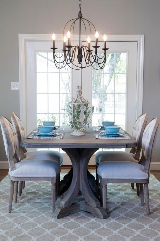 a vintage rustic dining zone with a stained dining table, upholstered chairs, a vintage metal chandelier and a beautiful lantern with greenery