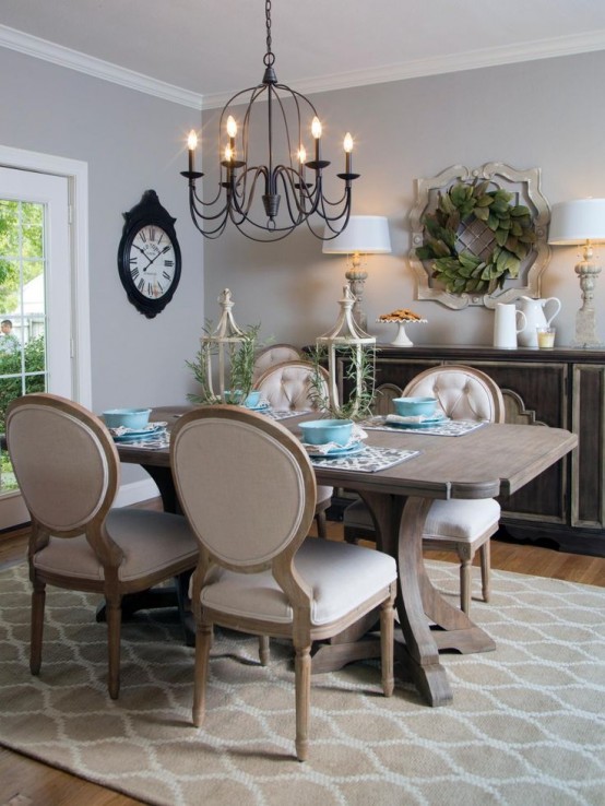 a neutral vintage dining space with grey walls, a large vintage credenza, a stained dining table and vintage chairs with neutral upholstery, a vintage metal chandelier