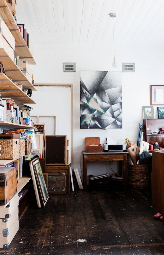 a mid-century modern home artist studio with open shelves, baskets for storage, desks and tables, ledges and lots of artwork