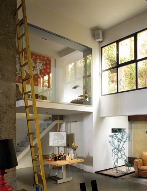 a small home artist nook with an easel, a large table with supplies and natural light coming inside through the window