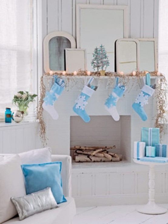 a creative Christmas mantel with lights, a dried leaf garland, blue and white stockings hanging on the mantel is super lovely