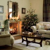 a Christmas mantel styled with a greenery garland, pillar candles and some lights, a branch with ornaments