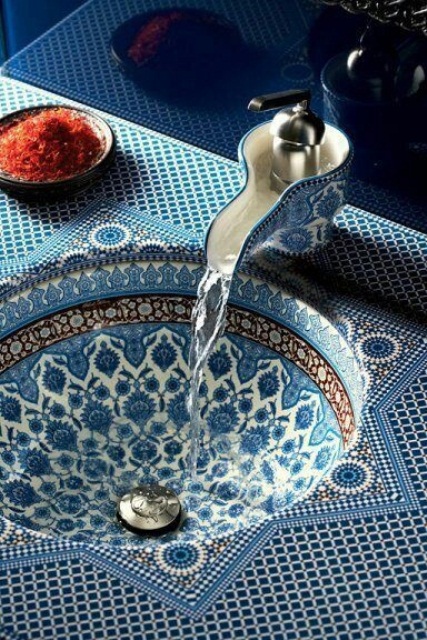 a blue patterned vanity with a painted bowl sink built in and a catchy faucet 