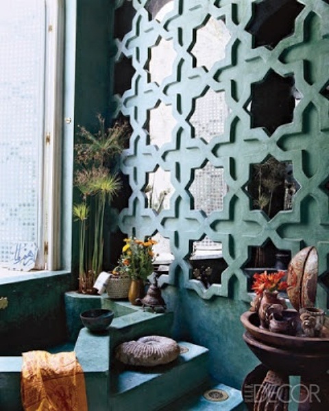 a plaster-covered bathroom done in turquoise, with a mirror wall done with star-shaped frames and potted blooms